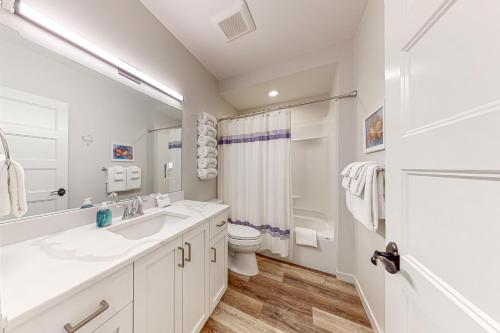 a white bathroom with a sink and a toilet at Penn Cove Strand #F in Coupeville