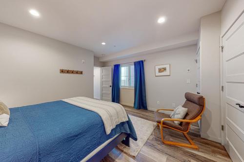 1 dormitorio con 1 cama azul y 1 silla en Penn Cove Strand #F en Coupeville