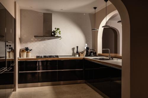 una cucina con armadi neri, lavandino e arco di Lighthouse View Apartment a Żebbuġ