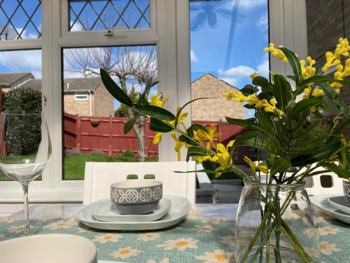 una mesa de comedor con un jarrón de flores. en Bright, Airy & Beautifully Decorated 3 Bedroom Home en Kettering