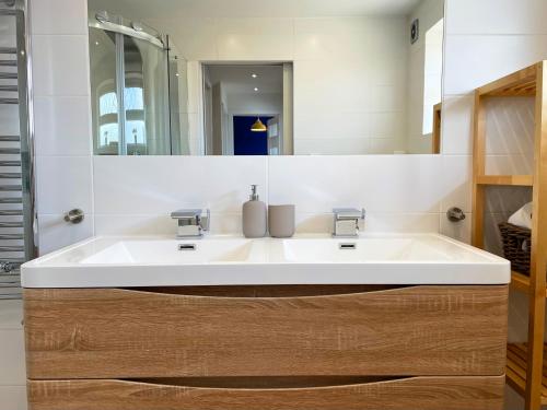 a bathroom with a white sink and a mirror at Bright, Airy & Beautifully Decorated 3 Bedroom Home in Kettering