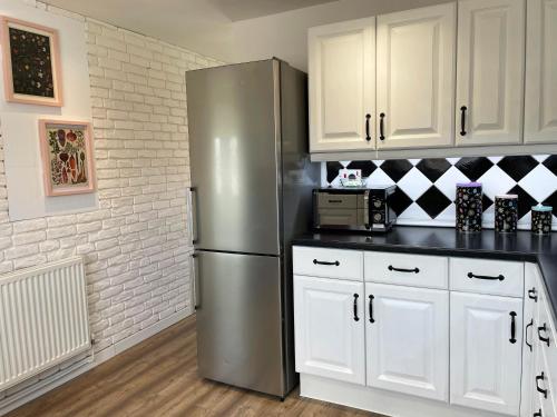 a kitchen with a stainless steel refrigerator and white cabinets at Bright, Airy & Beautifully Decorated 3 Bedroom Home in Kettering