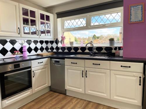 a kitchen with white cabinets and a sink and a window at Bright, Airy & Beautifully Decorated 3 Bedroom Home in Kettering