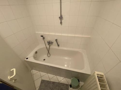 a white bath tub in a white tiled bathroom at Schöne 2-Raumwohnung in Dresden in Dresden