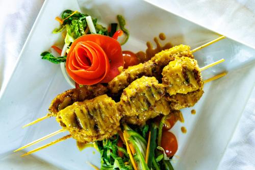 a plate of food with meat and vegetables on skewers at Shaka Caye All inclusive Resort in Belize City