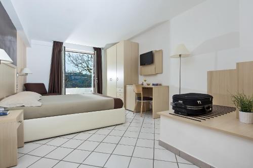 a hotel room with a bed and a desk with a suitcase at De Maria House in SantʼAgata sui Due Golfi