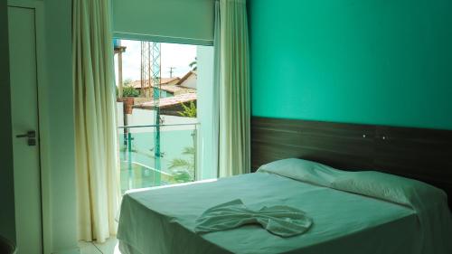 a bed with a bow on it in a room with a window at Gênova Palace Hotel in Acailandia