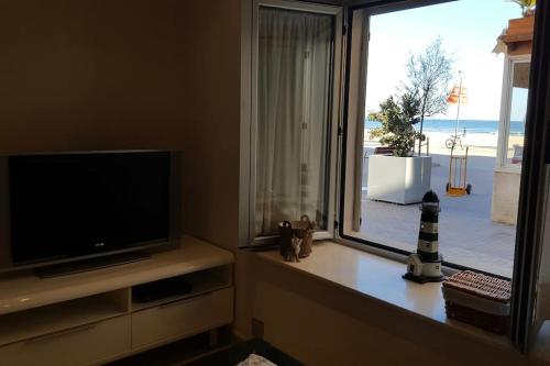 a living room with a flat screen tv and a window at Increíble casa frente al mar , planta baja in Torredembarra