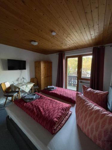 a bedroom with two beds and a table and a window at Pension zur Hammermühle in Wallenfels