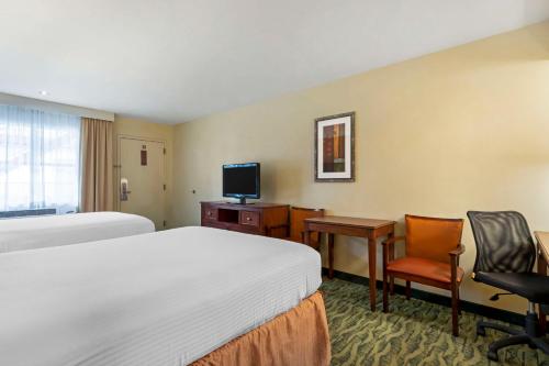 Habitación de hotel con 2 camas, escritorio y TV. en Best Western Mcallen Medical Center, en McAllen