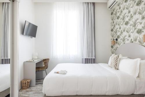 a white bedroom with a bed and a desk at Hôtel La Villa Juan Beach in Juan-les-Pins