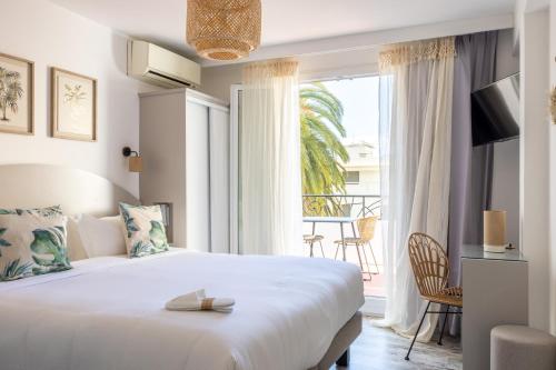 a bedroom with a large bed and a large window at H&ocirc;tel La Villa Juan Beach in Juan-les-Pins