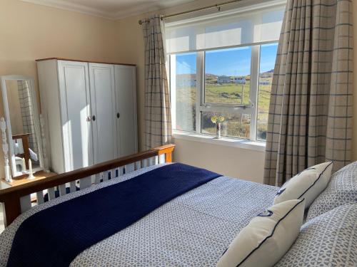 1 dormitorio con cama y ventana grande en Tigh-na-Greine, en Carloway