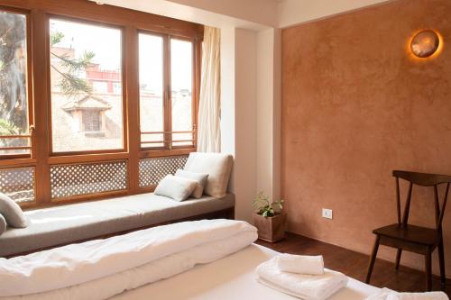 a living room with a large window and a couch at Newa Chen Historic House UNESCO in Pātan