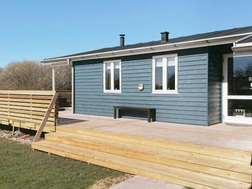 a blue house with a wooden deck in front of it at 8 person holiday home in Vestervig in Vestervig