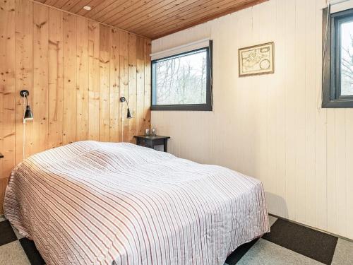 - une chambre avec un lit dans une pièce dotée de murs en bois dans l'établissement Holiday home Roslev IX, à Roslev