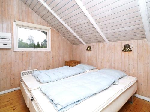 a bed in a room with wooden walls and a window at Holiday Home Dyssestræde in Dannemare