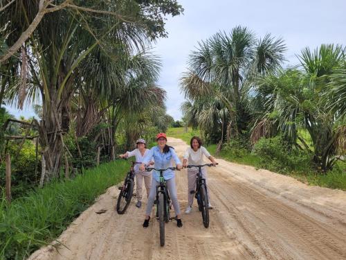three people riding bikes down a dirt road at Amaca Eco Station in Iquitos