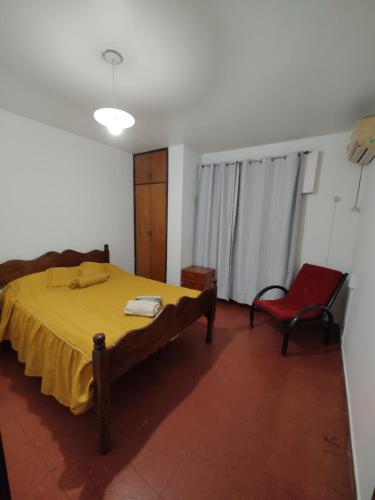 1 dormitorio con 1 cama amarilla y 1 silla roja en Edificio Engwald en Eldorado