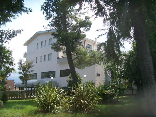 a white building with trees and plants in front of it at Hotel Du Parc in Atri