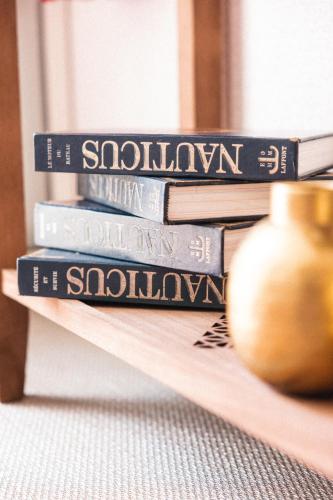 a stack of books sitting on a shelf with a vase at Hôtel La Villa Juan Beach in Juan-les-Pins