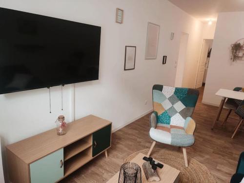 sala de estar con silla y TV de pantalla plana en Maison scandinave avec garage, en Roubaix