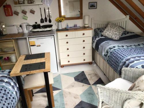 a small bedroom with a bed and a kitchen at Lovely studio apartment near camborne in Camborne