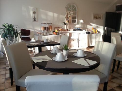 a dining room with a table and white chairs at Hôtel Beausoleil in Montélimar