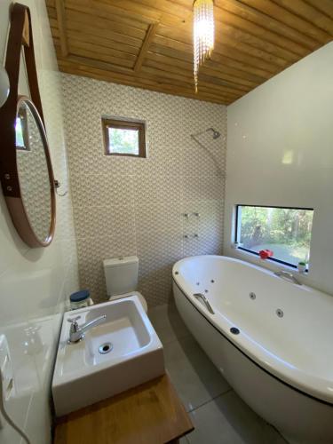 a bathroom with a large tub and a sink at Chalé Verdant in Canoinhas