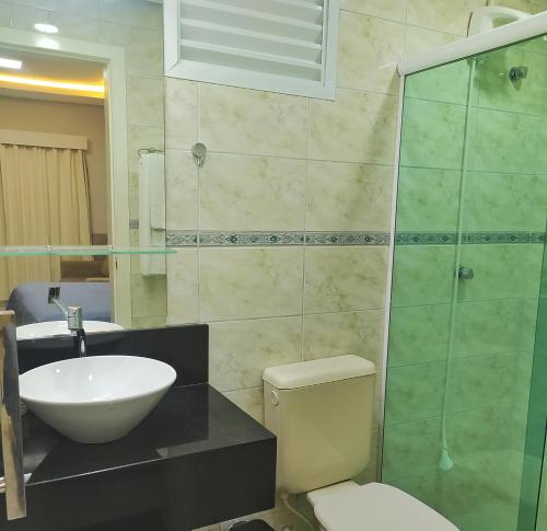 uma casa de banho com um lavatório, um WC e um chuveiro em Riviera Flat em Bertioga