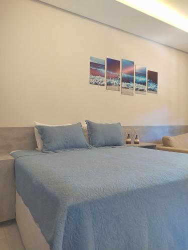 a bedroom with a bed with three paintings on the wall at Riviera Flat in Bertioga