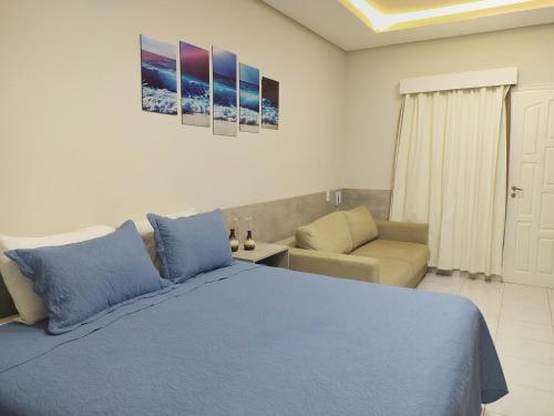 um quarto com uma cama azul e um sofá em Riviera Flat em Bertioga