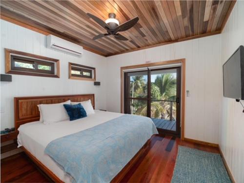 1 dormitorio con 1 cama y ventilador de techo en Three by the Sea en San Pedro