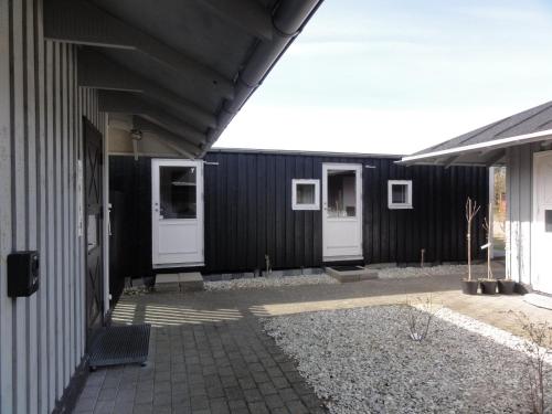 a black building with white doors and a courtyard at Tornby Strand Camping Rooms in Hirtshals