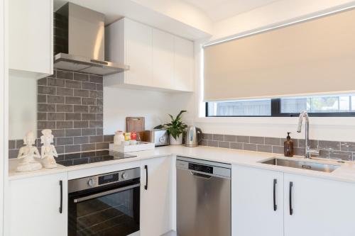 a kitchen with white cabinets and a sink and a window at Grace Road Getaway in Tauranga