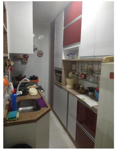 una pequeña cocina con armarios blancos y fregadero en Apartamento recreio, en Río de Janeiro