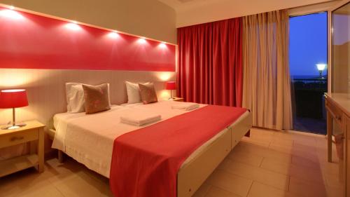 a bedroom with a large bed with a red wall at Sunrise Resort Hotel in Mithymna