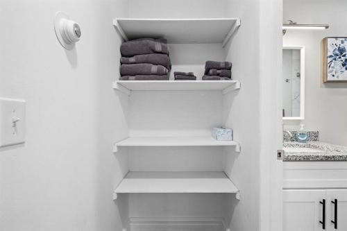 ein Badezimmer mit weißen Regalen, Handtüchern und einem Waschbecken in der Unterkunft Brand New 1BR Flat, Cozy King Suite in Mount Clemens