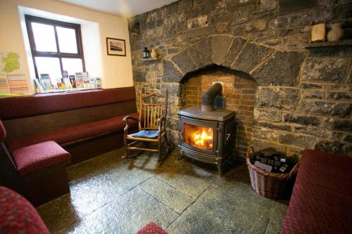 a stone fireplace in a room with a stove at Aille River Tourist Hostel and Campsite Doolin in Doolin