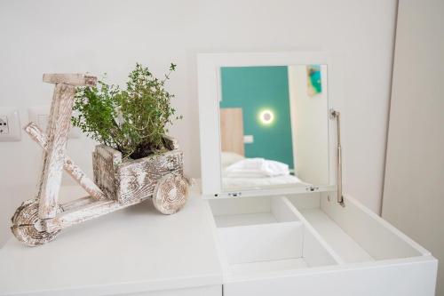 a mirror and a vase with a plant on a wall at B&B DieMme Amalfi Coast in Vietri sul Mare