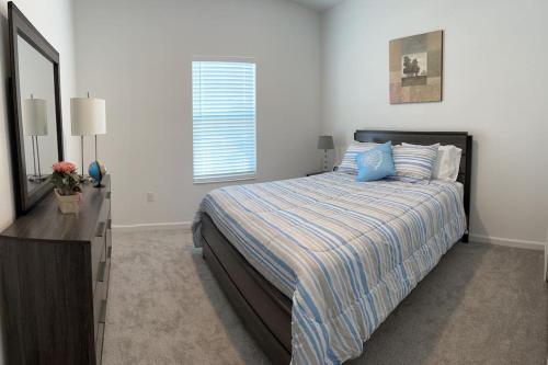 - une chambre avec un lit, une commode et un miroir dans l'établissement * Brand New Vacation Home *, à Haines City