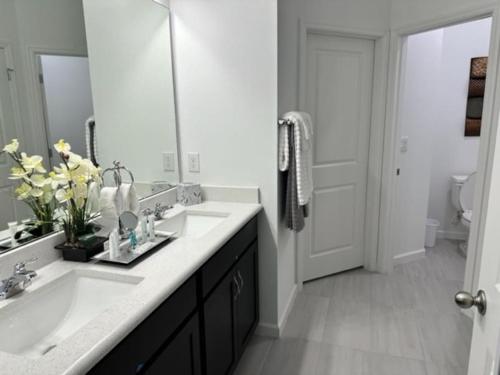 La salle de bains est pourvue de 2 lavabos et d'un grand miroir. dans l'établissement * Brand New Vacation Home *, à Haines City