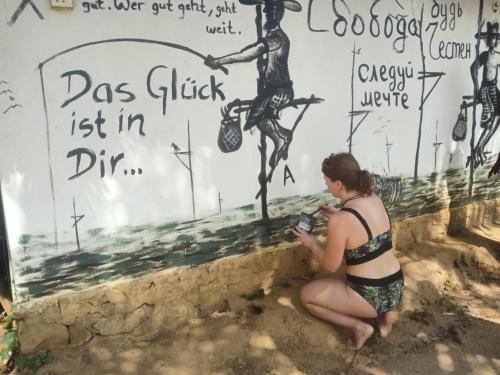 a woman in a bikini sitting in the sand in front of a wall at Beach Bungalow Yala in Kirinda