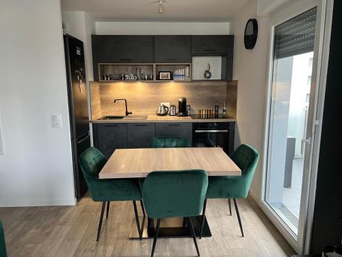 une cuisine avec une table en bois et des chaises vertes dans l'établissement Gorgeous Apartment near Paris & Disneyland, à Fontenay-sous-Bois
