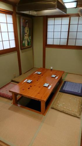 a large wooden table in a room with windows at Travel Inn Ikuta in Minabe