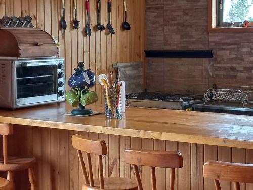 a kitchen with a wooden counter with chairs and a microwave at Casa Familiar Reserva Humedal in El Convento