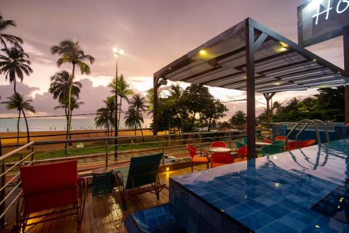 un complejo con una piscina con sillas y una mesa en Netuanah Praia Hotel, en João Pessoa