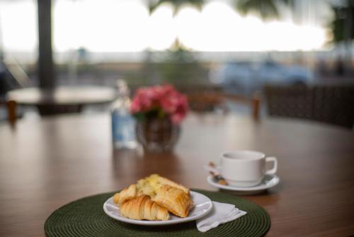 a plate of croissants and a cup of coffee on a table at Netuanah Praia Hotel in João Pessoa