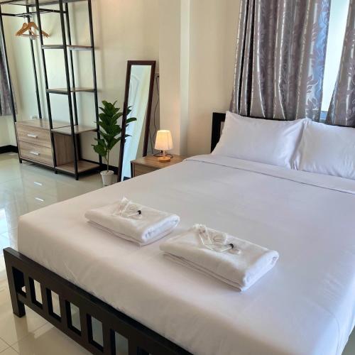 a bedroom with a large white bed with towels on it at Ivory House Sriracha in Si Racha