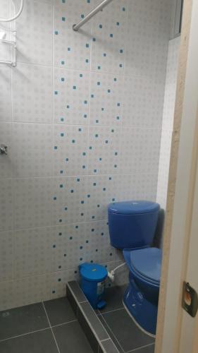 a bathroom with a blue toilet and a white tiled wall at Habitaciones en Acogedora estancia en pleno centro de Ibagué in Ibagué